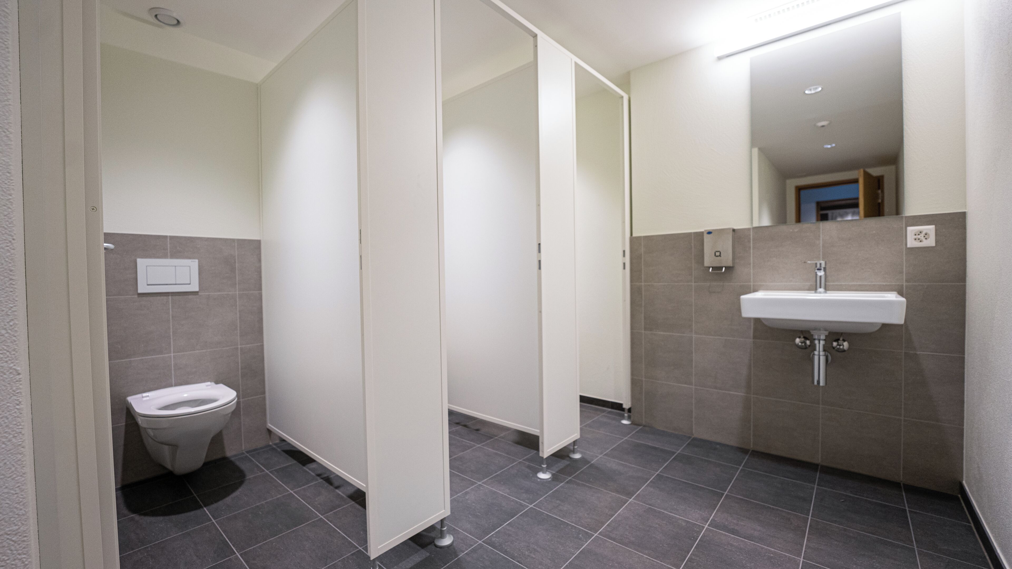 A modern bathroom with a toilet, a sink, and a mirror.