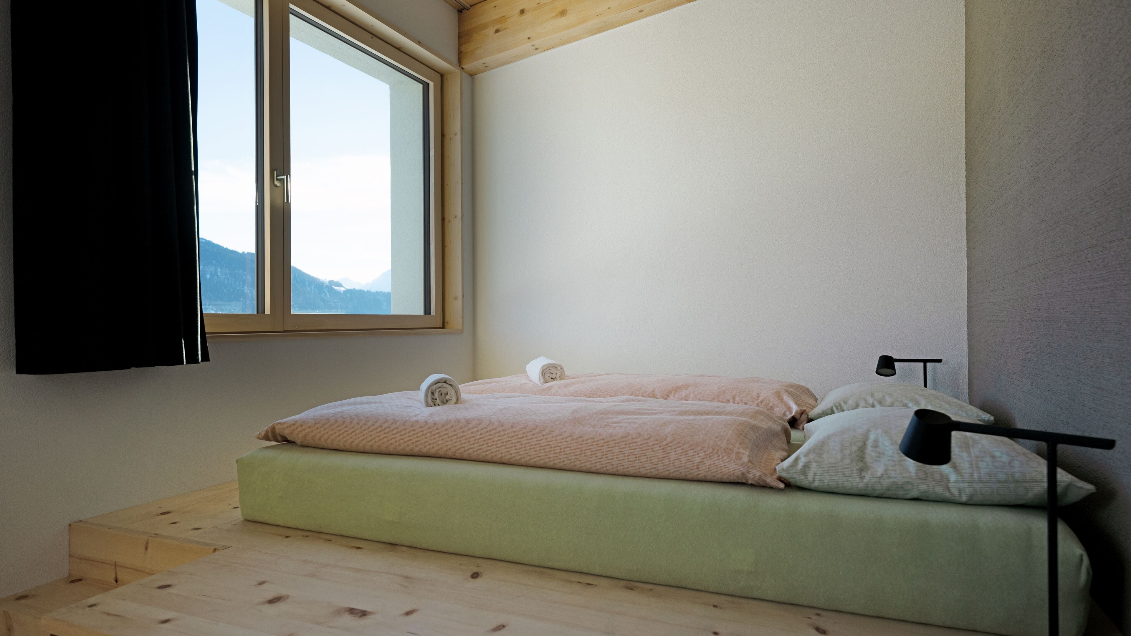 A room with a bed, a window, and a wooden floor.