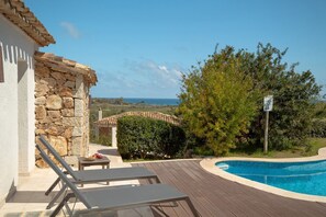 Una piscina al aire libre, sillones reclinables de piscina