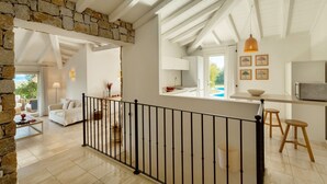 A spacious living area with a stone wall, a white sofa, a coffee table, and a black railing. - VILLA GELSOMINO, 500 meters from the sea with garden, private pool, and sea view (Castiadas)