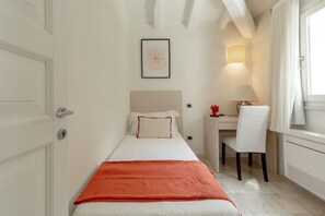 A bedroom with a bed, a desk, a chair, a lamp, and a window with curtains. - VILLA GELSOMINO, 500 meters from the sea with garden, private pool, and sea view (Castiadas)