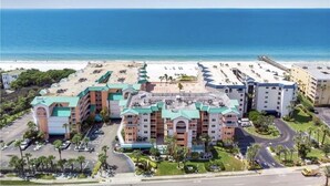 A hotel with multiple buildings, a parking lot, and a view of the ocean. - The Seascape Premier Beachfront Cottage: Gulf View, Pool, Hot Tub, BBQ, WiFi (Indian Shores)