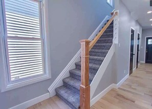 A staircase with wooden handrails and patterned carpet, leading to a dark door.