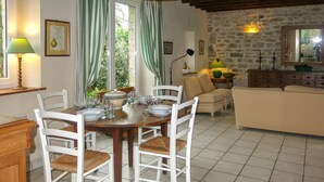 Un coin repas avec une table en bois dressée pour quatre personnes, entourée de chaises blanches à assise tissée.