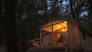 Uma cabana de madeira com varanda, espaço de jantar e bicicletas.
