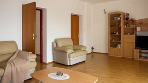 Una sala de estar con sofá, sillón, mesa de centro, mueble para televisión y armarios de madera.