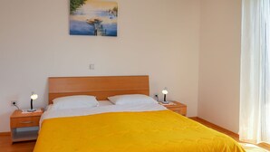 Un dormitorio con cama de madera, ropa de cama blanca, dos lámparas de noche y un cuadro en la pared.