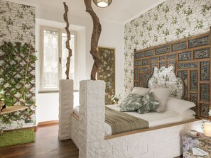 A bedroom with a stone wall, a bed with a wooden headboard, and a decorative wall panel. - St. Peter mirror Romantic view (Roma)