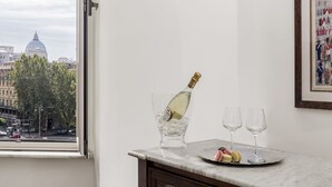 Ett rum med en bänkskiva i marmor, en flaska champagne, två glas och macarons på ett fat.