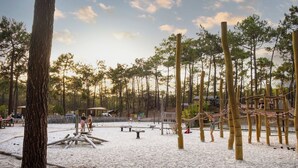 A playground with sand, wooden structures, and trees. - Huttopia Lac de Carcans (Carcans)