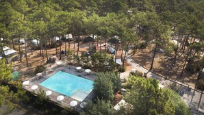 An aerial view of a resort with a swimming pool surrounded by trees and outdoor seating areas. - Huttopia Lac de Carcans (Carcans)