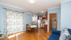Ein Wohnzimmer mit einem blauen Sofa und einem Essbereich mit Tisch und Stühlen.