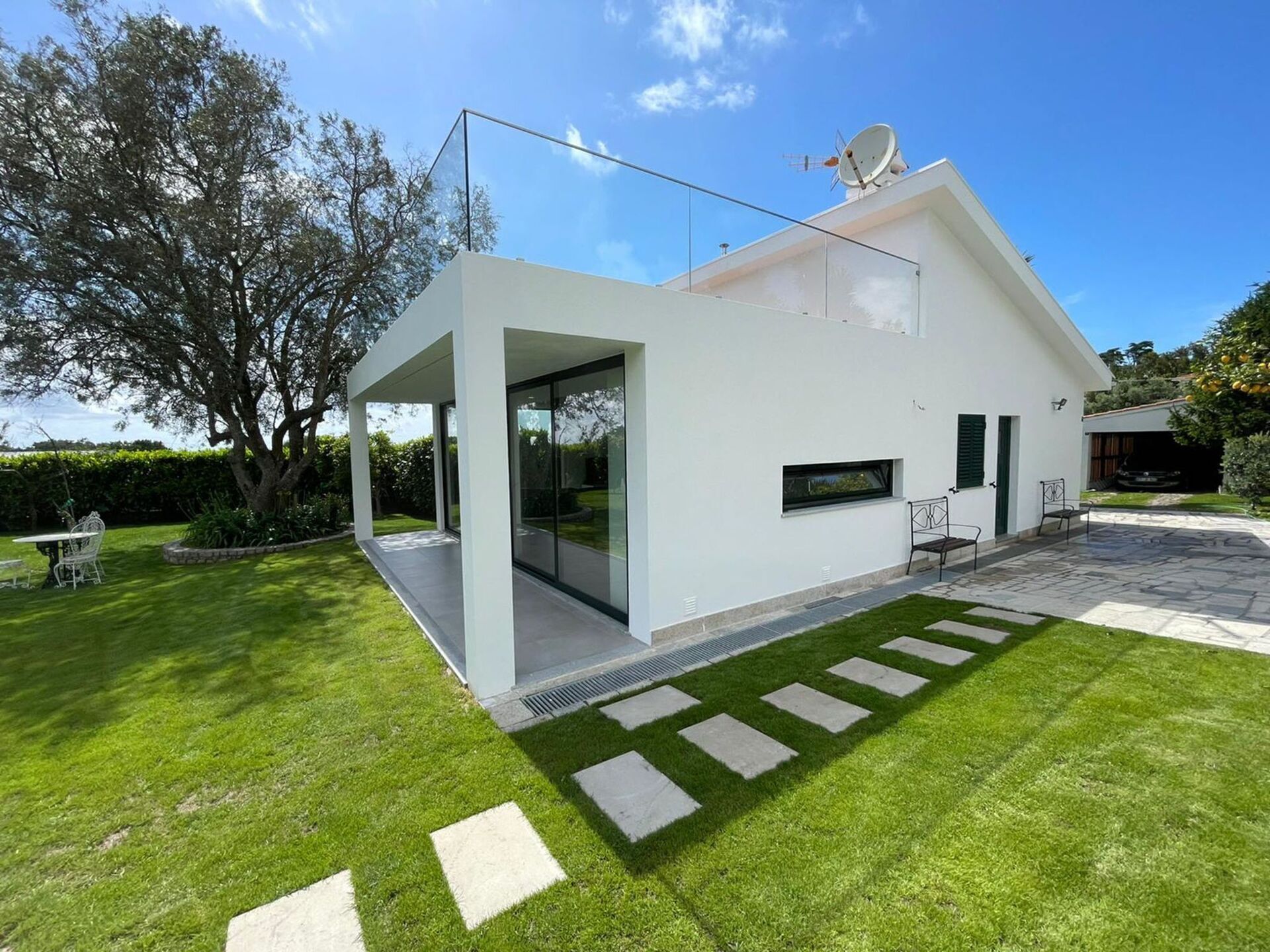 Ein modernes Haus mit Glastür, einem Kiesweg und einem gepflegten Rasen.