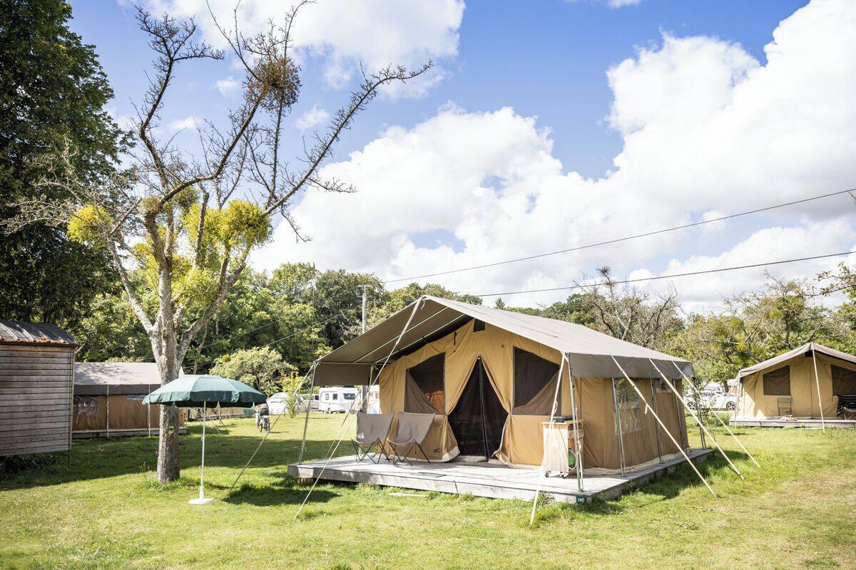 A campsite with a large tent, a smaller tent, and a wooden cabin.