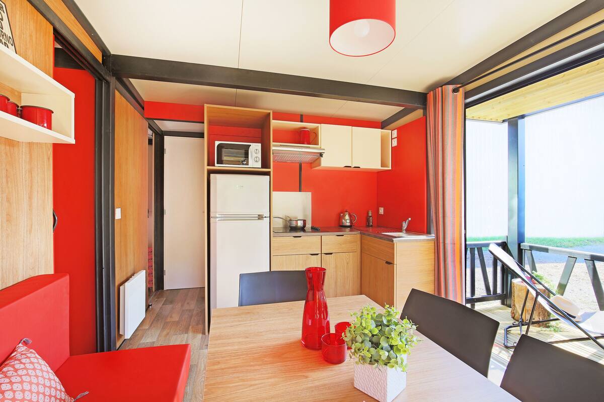 A compact kitchen with a microwave, refrigerator, and wooden cabinets.