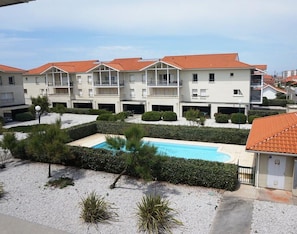 A multi-story hotel with a swimming pool, surrounded by manicured hedges and a gravel area. - BiscaOcean - T3 seafront apartment with pool and terrace (Biscarrosse Plage)