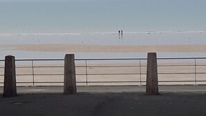 Vista de una playa con arena y una barandilla de metal.