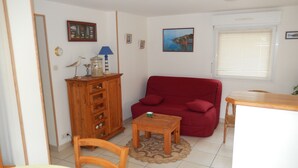Una sala de estar con un sofá rojo, un mueble de madera y una mesita.