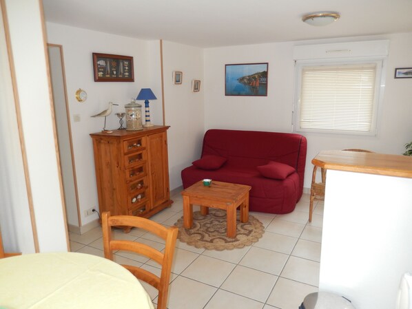 Un salon avec un canapé rouge, un meuble en bois et une petite table.