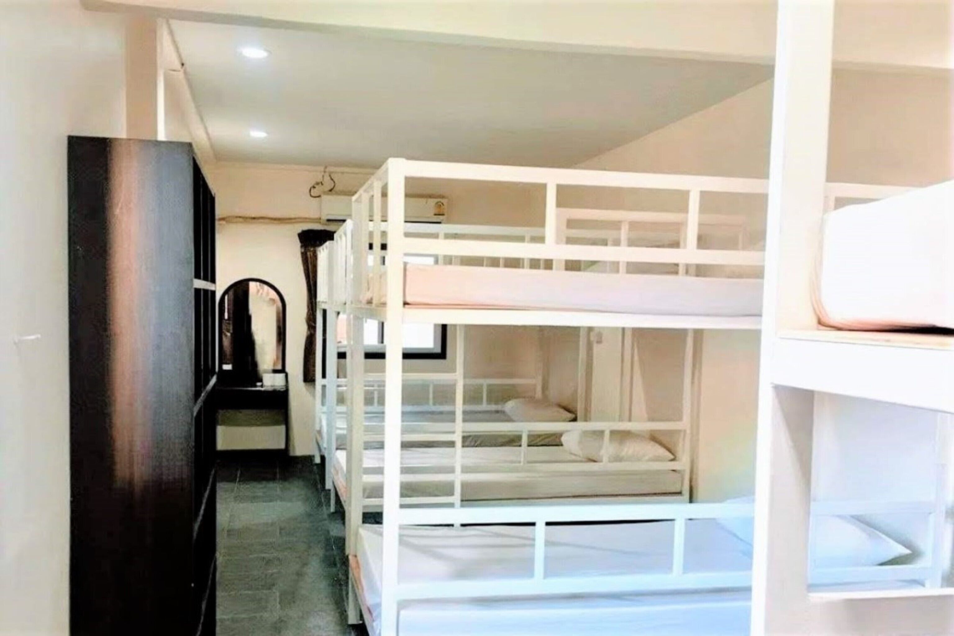 Una habitación con literas, un armario oscuro y una pequeña mesa con una silla.