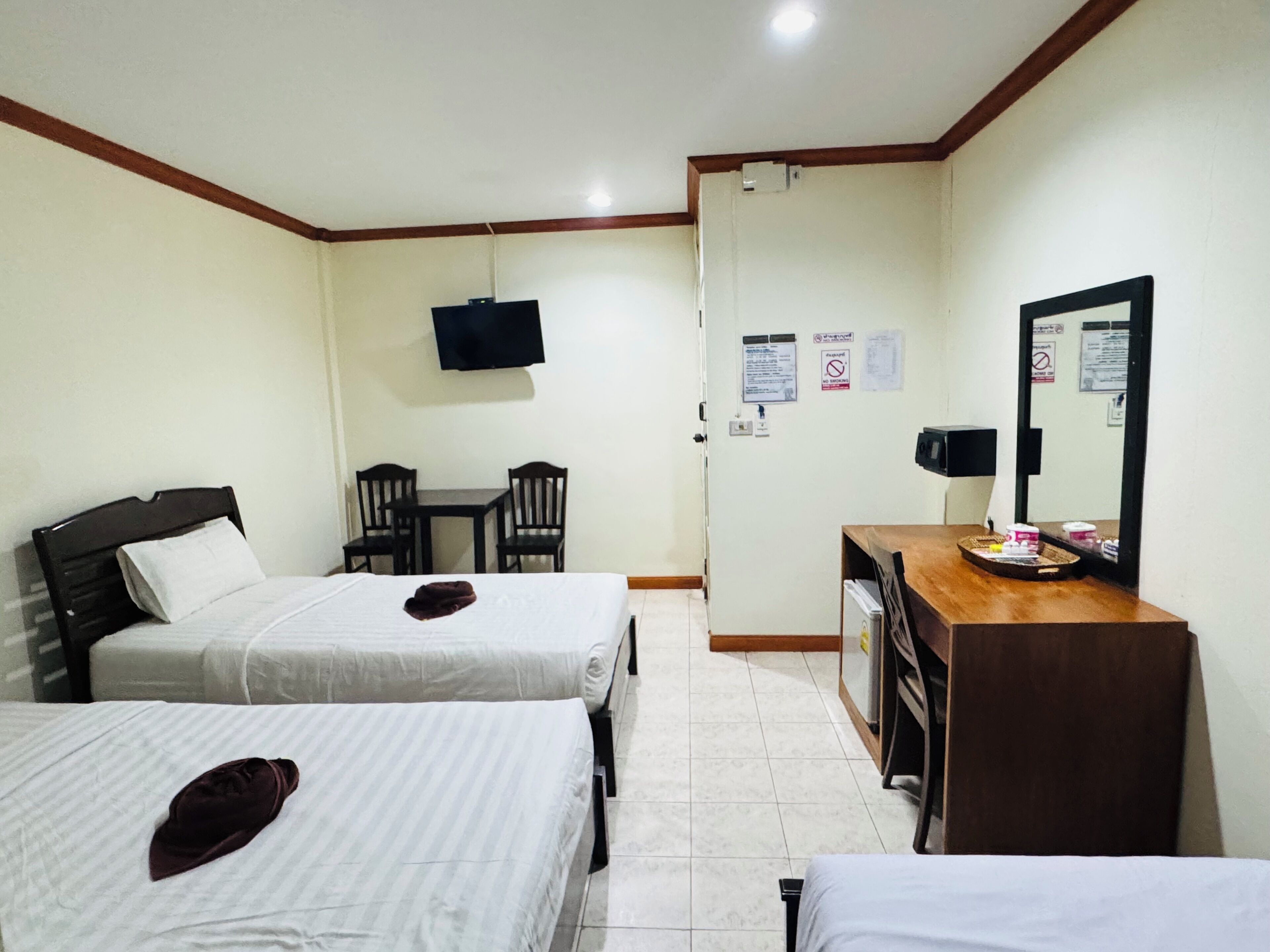 Quarto de hotel com duas camas, uma escrivaninha, uma cadeira, uma televisão e um espelho.