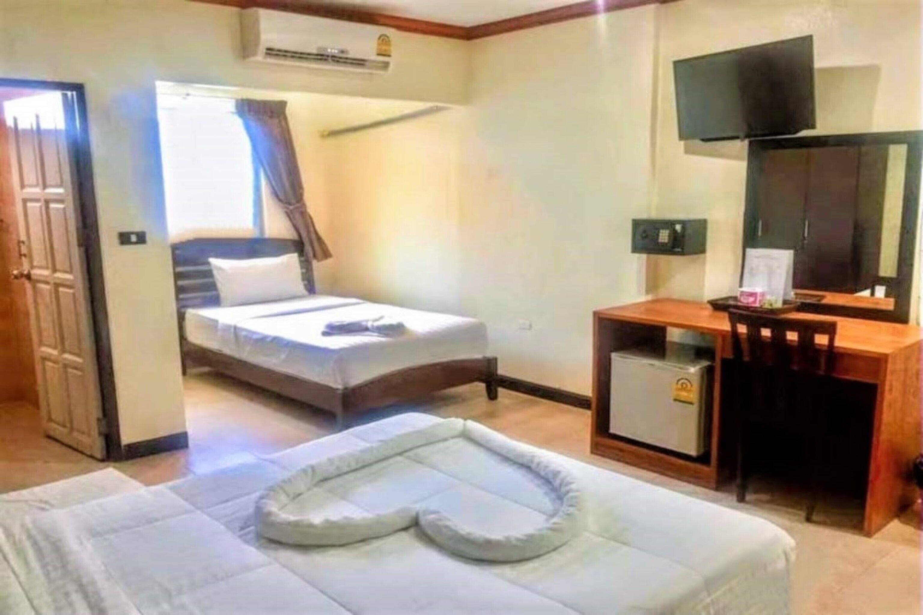 A hotel room with a bed, a desk with a chair, a television, and a small refrigerator.