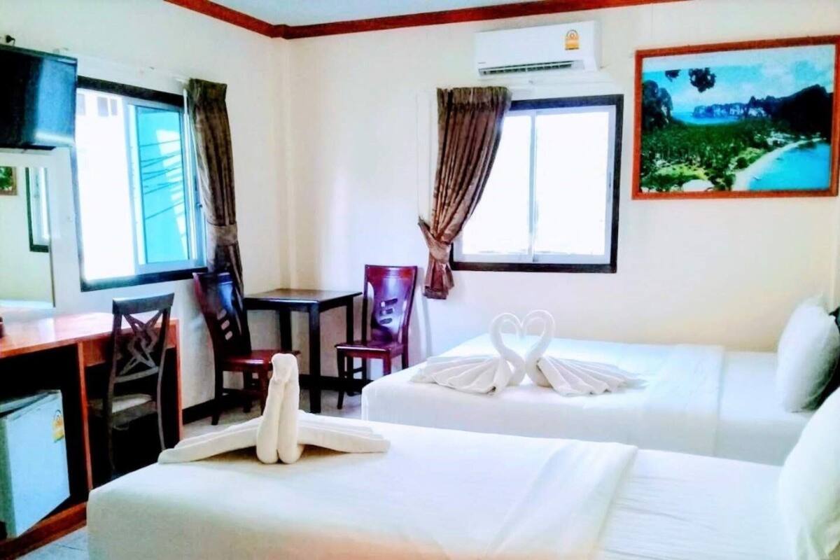 A hotel room with two beds, a desk, a chair, a small table, and a painting on the wall.