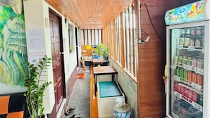 A narrow hallway with wooden ceiling panels, a vending machine on the right, and a potted plant on the left. - Golden Bee PhiPhi Hostel (Ko Phi Phi)
