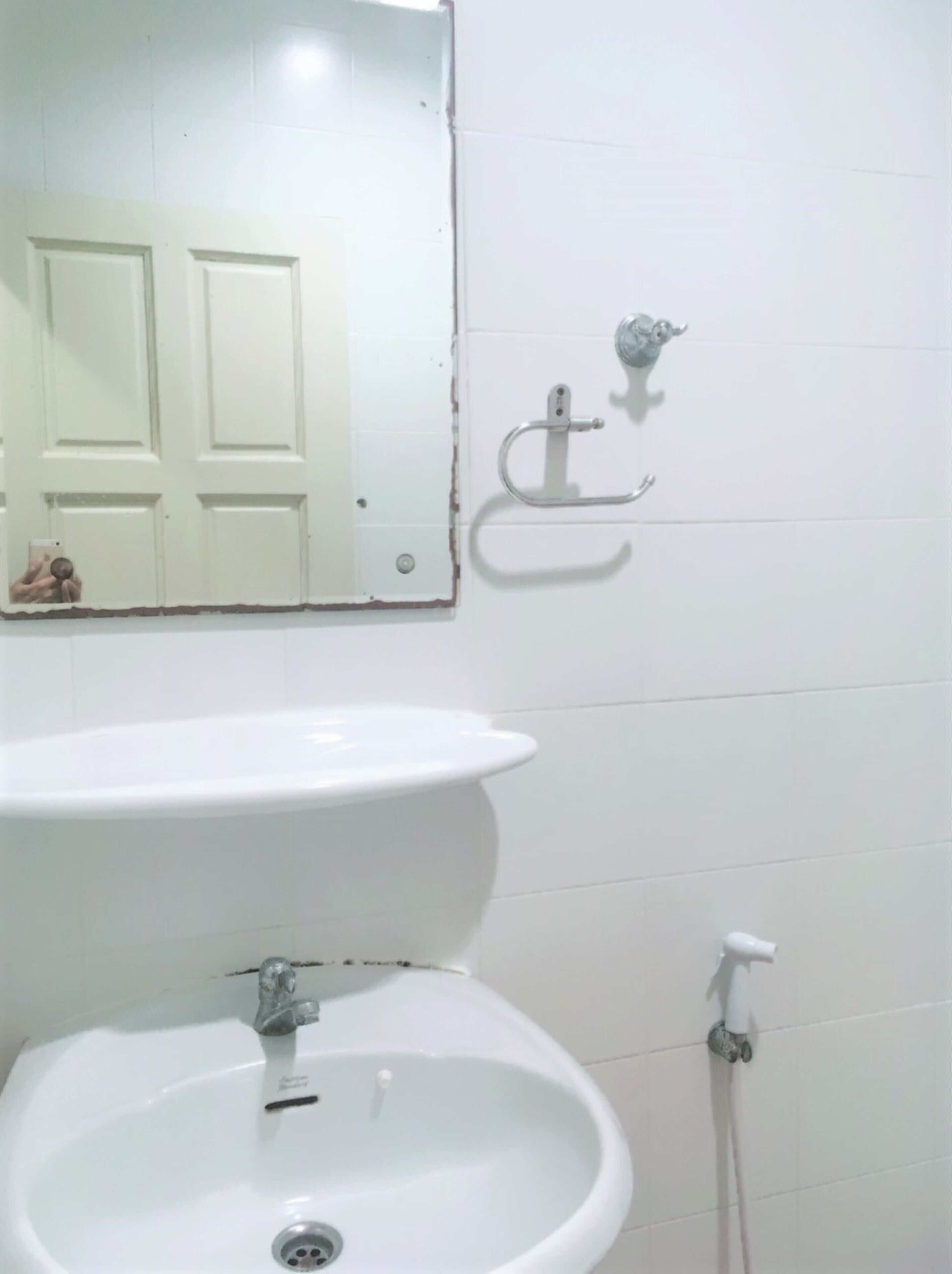 Un baño con un lavamanos blanco, un espejo y una puerta.