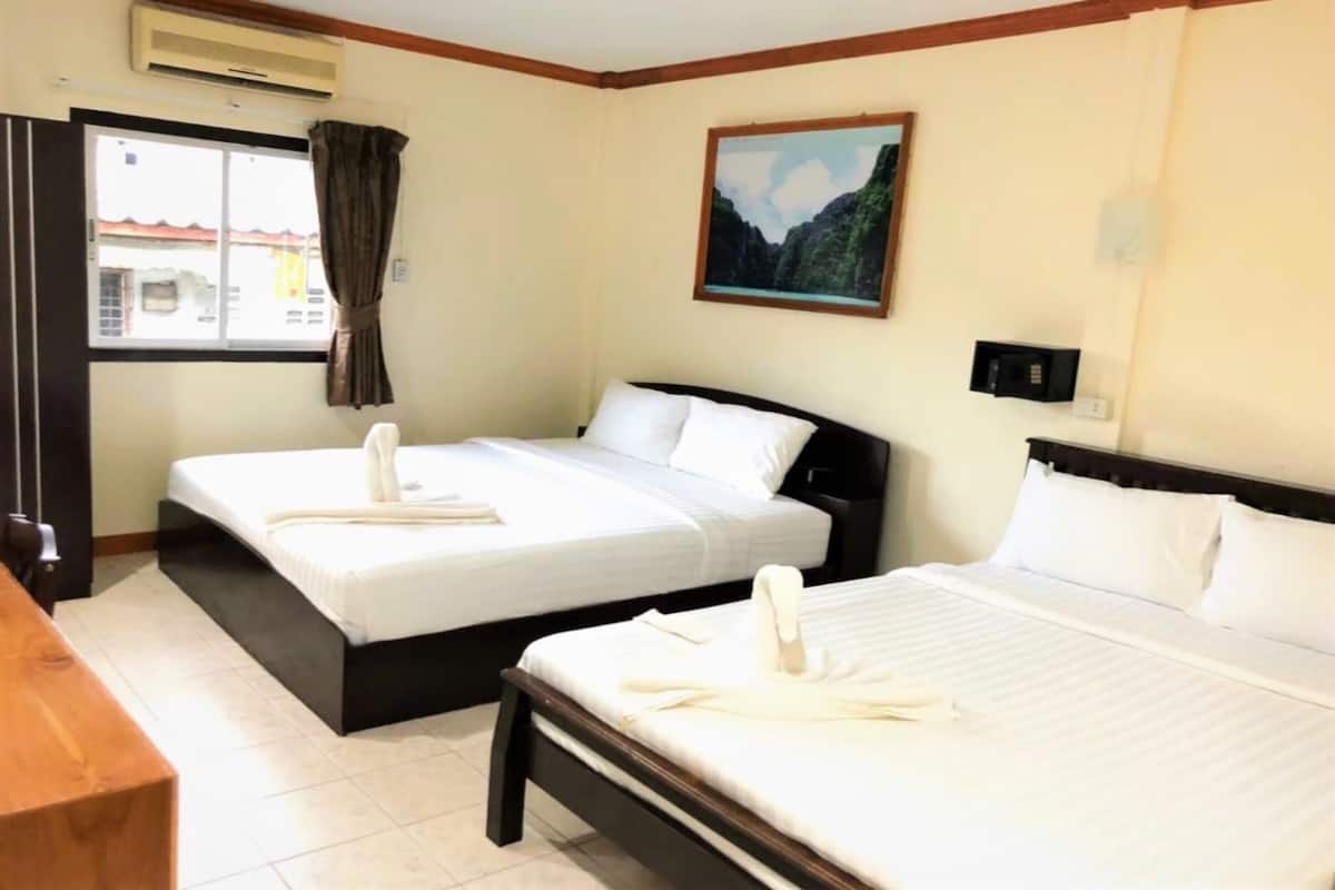 A hotel room with two beds, a wooden desk, a window with curtains, and a painting on the wall.