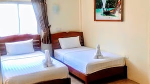 A hotel room with two single beds, a large window with curtains, an air conditioning unit, and a framed picture of a boat on water. - Golden Bee PhiPhi Hostel (Ko Phi Phi)