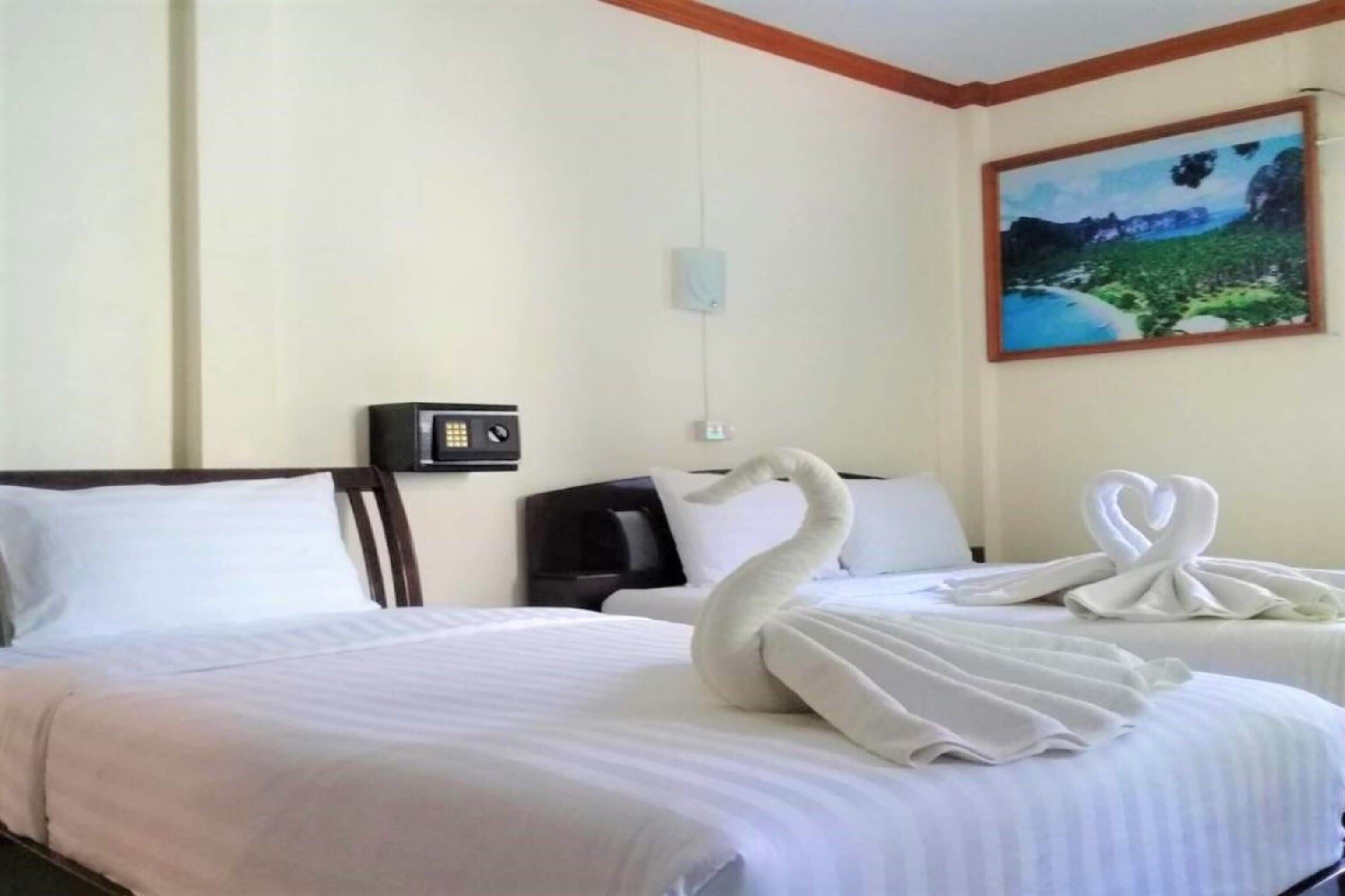 A hotel room with a bed, a painting on the wall, and a swan-shaped towel on the bed.