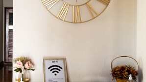 Un mostrador de recepción con un reloj de pared grande, un letrero de Wi-Fi y una tarjeta con la contraseña enmarcada.