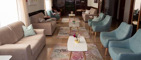 Una sala de estar moderna con un sofá, sillones, una mesita de centro y un televisor.
