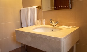 A bathroom with a beige sink, a mirror, and a towel hanging on the wall. - Hotel Santa Cecília (Ourem)