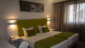 Una habitación de hotel con cama doble, dos mesitas de noche, un escritorio y una silla.