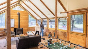 A cozy wooden interior with a foosball table, a sofa, and a fireplace.