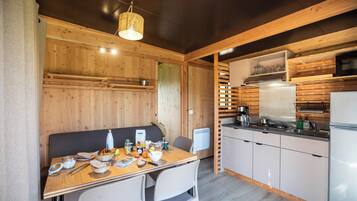A compact kitchen with wooden walls, a dining table with breakfast items, and modern appliances.