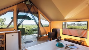 A cozy, triangular-roofed room with a bed, a small desk, a chair, and a large window offering a scenic view. - Huttopia Meursault (Meursault)