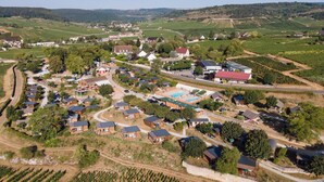 An aerial view of a rural village with houses, fields, and a swimming pool. - Huttopia Meursault (Meursault)