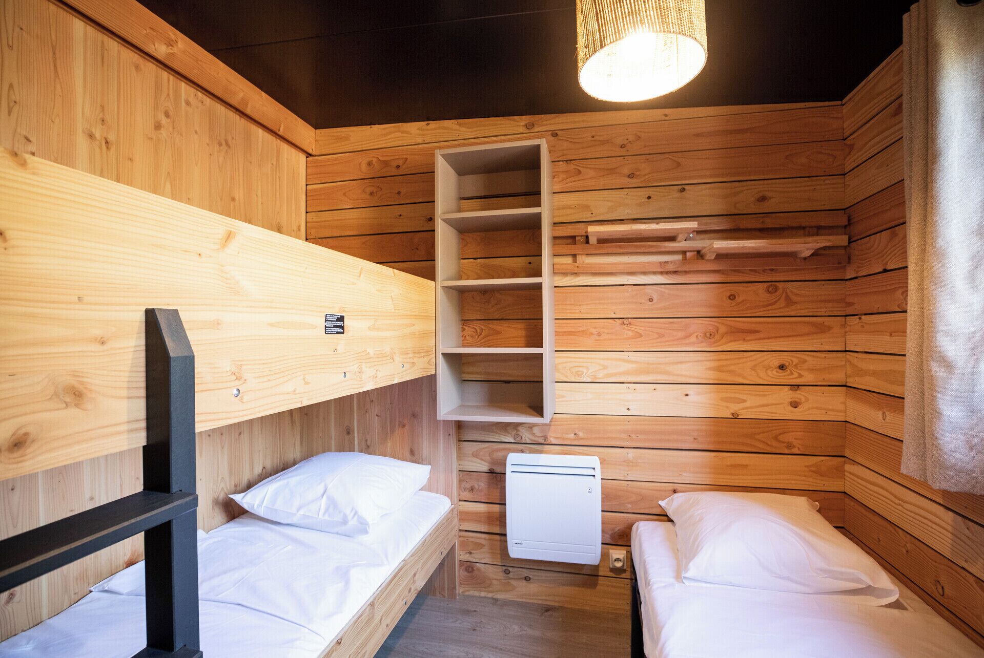 Een houten kamer met stapelbedden, een witte verwarming en een hanglamp.
