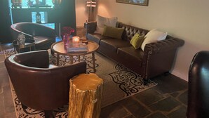 Een gezellige woonkamer met een leren bank, een bijzettafeltje en een decoratieve vaas.