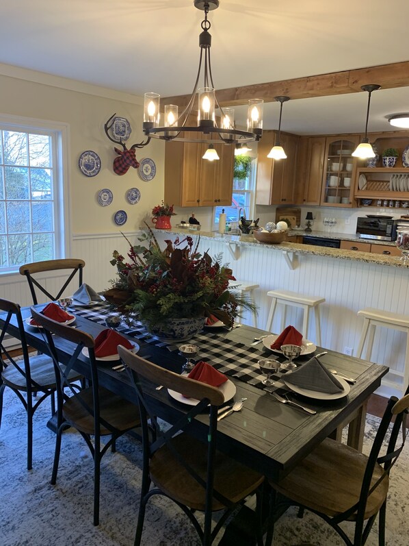 A dining area with a checkered tablecloth, wooden chairs, and a central floral arrangement.