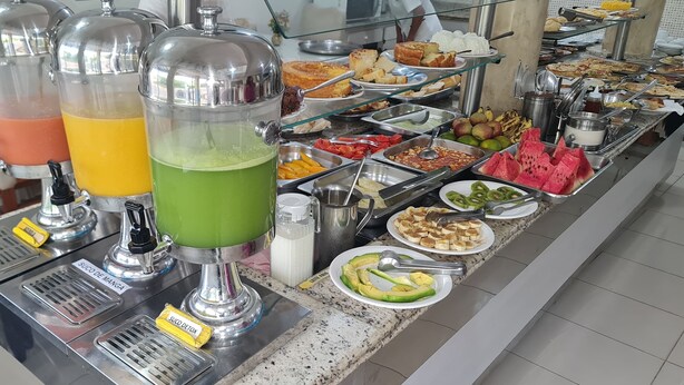 Ein Buffet mit verschiedenen Speisen und drei Getränkespendern.