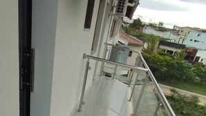 Ein Balkon mit Metallgeländer, einer Tür und einer Klimaanlage.