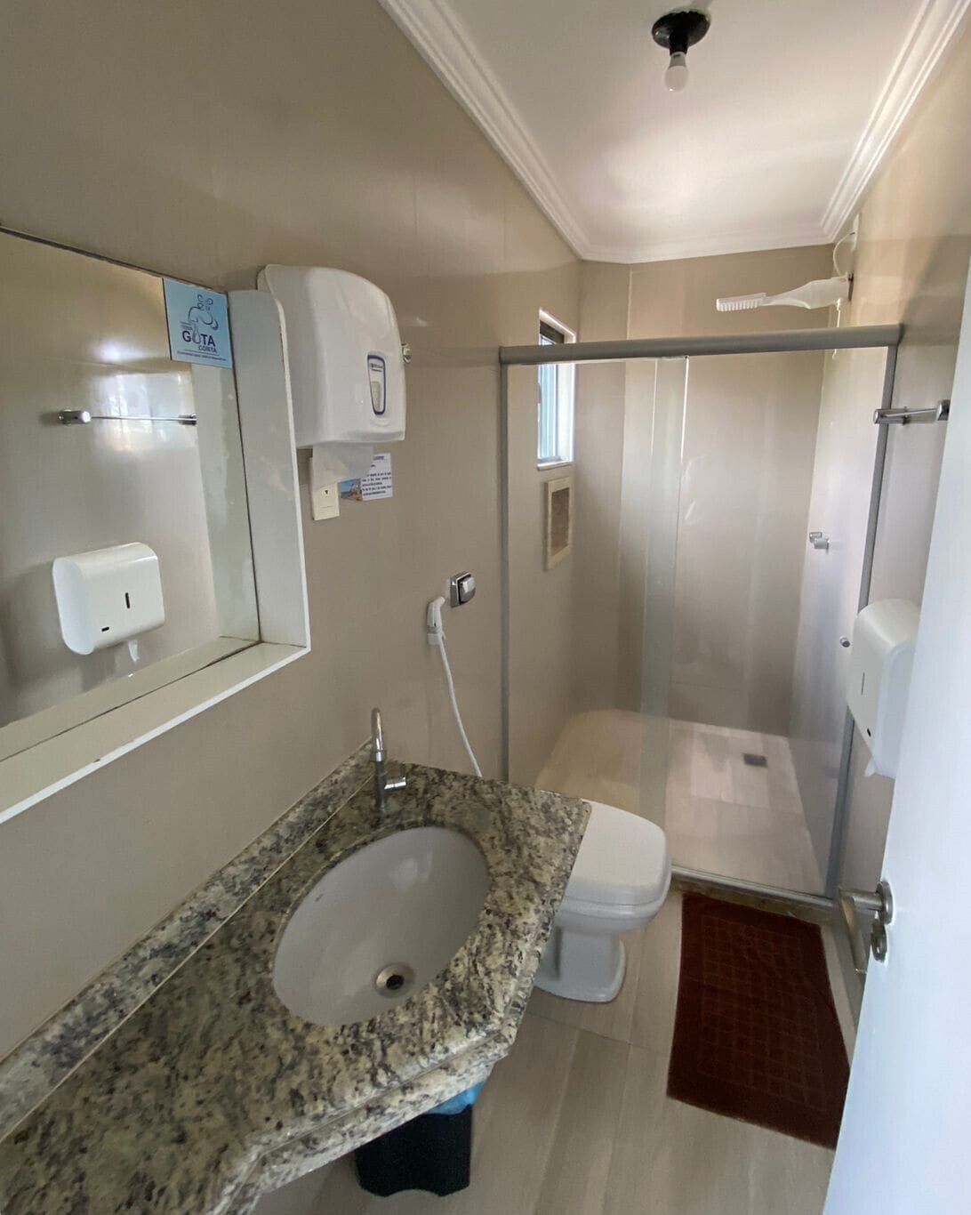 Un baño con lavamanos de granito, inodoro y cabina de ducha de cristal.