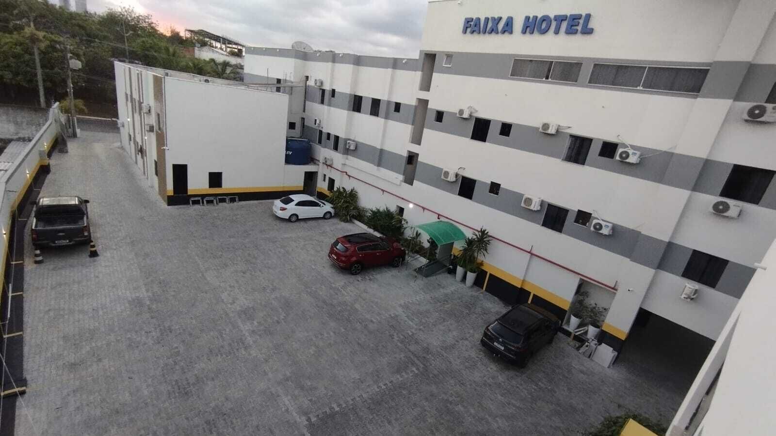 Ein Hotel mit Parkplatz, mehreren Autos und einem grünen Sonnenschirm.