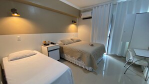 Ein Hotelzimmer mit zwei Betten, einem kleinen Schreibtisch, einem Stuhl und einer Klimaanlage.