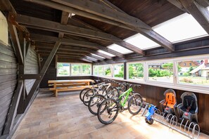 A covered bike parking area with wooden benches and a view of the outdoors. - Lipno Lake Chalet (Prední Výton)