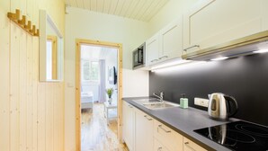 A modern kitchen with wooden flooring, a black countertop, and stainless steel appliances. - Lipno Lake Chalet (Prední Výton)